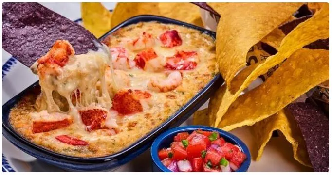 Red Lobster creamy lobster-swiss dip in skillet topped with melted cheese, served beside tortilla chips.