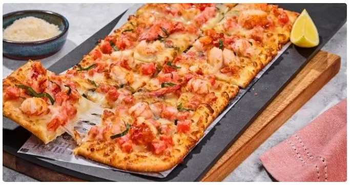Red Lobster lobster-mango flatbread on wooden board showing crispy crust, cheese melt and fresh herbs.